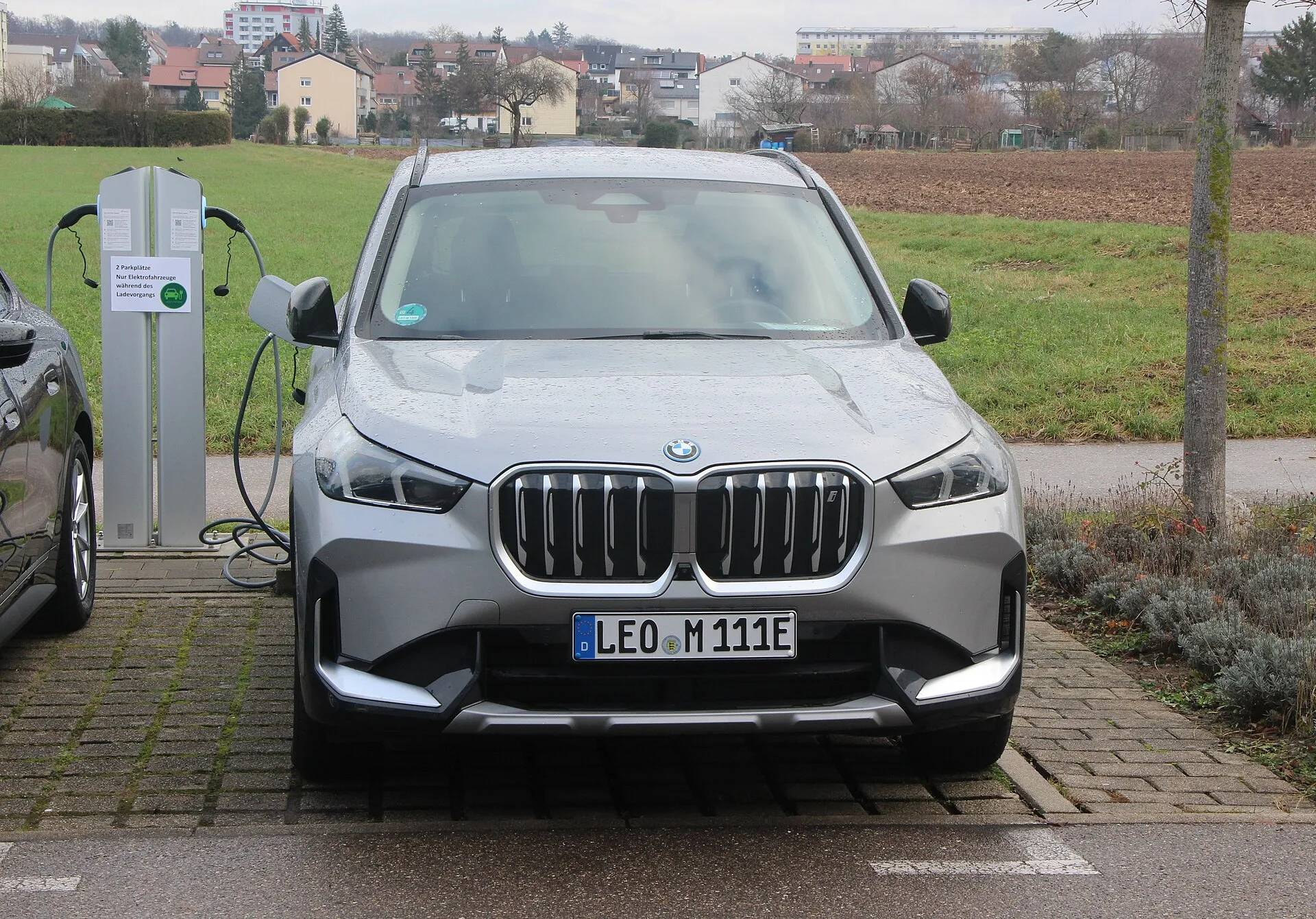 BMW iX1 חשמלית קומפקטית בצבע כהה על רקע עירוני
